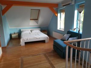 a bedroom with blue walls and a bed and a blue couch at Vetrovi šumijo I in Kapele