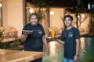 a woman and a man holding plates of food and drinks at Private Room Kayu Bunga in Canggu