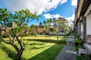 a garden with grass and trees and a house at Private Room Kayu Bunga in Canggu