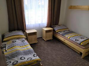 2 łóżka pojedyncze w pokoju z oknem w obiekcie Penzion Sloup w mieście Sloup