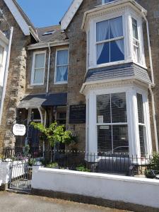 a brick house with a fence in front of it at Duporth Guest House in Penzance