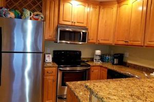 eine Küche mit einem Kühlschrank aus Edelstahl und Holzschränken in der Unterkunft Grand Caribbean in Pensacola