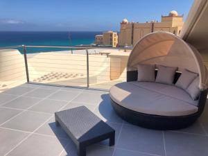 a bed sitting on top of a balcony with the ocean at Fuertevillage in Costa Calma