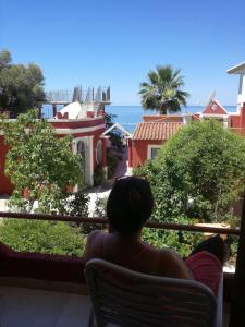 a woman sitting on a chair looking out at the ocean at Madalenas B&B in Pelekas