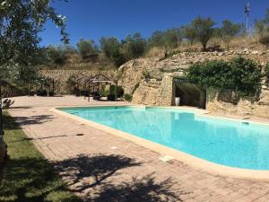 a swimming pool next to a stone building with a mountain at Agriturismo Baglio Pollicarini in Pergusa