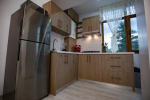 uma cozinha com um frigorífico de aço inoxidável e armários de madeira em Apartament Natalia em Tîrgu Ocna