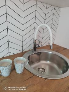 a kitchen sink with two cups on a counter at Apartments Natalija & Ante in Grebaštica