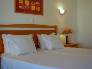 a bedroom with a bed with white pillows and a lamp at Luz Bay Hotel in Luz