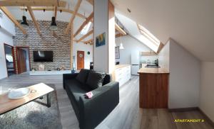 a living room with a couch and a table and a kitchen at Apartamenty Amalia in Szary Dwor