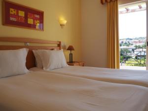 a bedroom with a large white bed with a window at Luz Bay Hotel in Luz