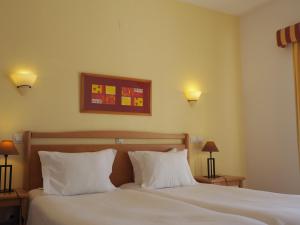 a bedroom with a white bed with two pillows at Luz Bay Hotel in Luz