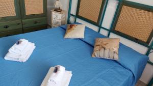 a bedroom with a blue bed with towels on it at A due passi dal mare in Fontane Bianche