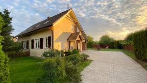 a yellow and white house with a driveway at Dom murowany Siedlisko in Sarbinowo