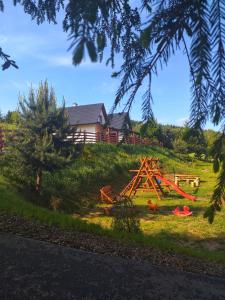 um quintal com um parque infantil de madeira na relva em Bieszczadzki Bohater Domki 533-502-137 em Polańczyk