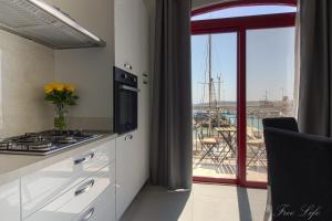 a kitchen with a stove and a view of a harbor at Mgarr Waterfront Cosy Apartment 3 by Ghajnsielem Gozo in Mġarr