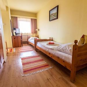 a bedroom with two twin beds and a rug at Il Gallo Nero - Fekete Kakas Étterem és Panzió in Szombathely