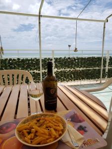 a table with a plate of pasta and a bottle of wine at Incantevole casa sul mare vicino a Roma in Nettuno