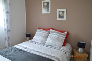 a bedroom with a bed with white sheets and red pillows at L Hibiscus in Jonzac +3 photos