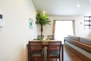 une salle à manger avec une table, des chaises et un palmier dans l'établissement E-horizon Resort コンドミニアム名護E, à Nago