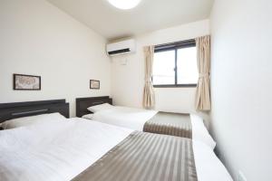 - une chambre avec 2 lits et une fenêtre dans l'établissement E-horizon Resort コンドミニアム名護E, à Nago