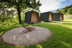 a wooden bench sitting in the grass in front of some huts at Glamping Health Resort in Kamnik