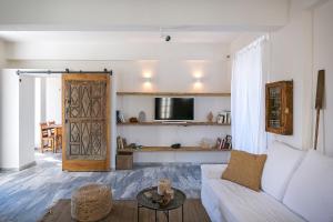 a living room with a white couch and a sliding door at Spitia Santorini Villa Collection in Oia
