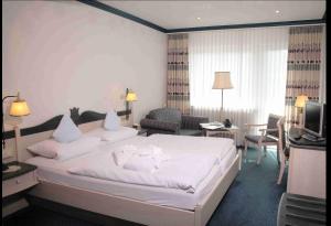 a bedroom with a large white bed and a living room at Wellnesshotel Bürgerstuben in Willingen