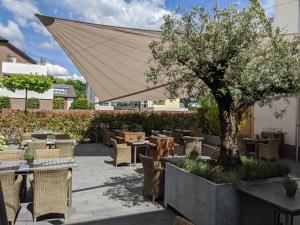 a patio with tables and chairs and a tree at Hotel Schmachtendorf in Oberhausen