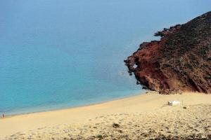 Siourdas Mykonos Villas في آغيوس سوستيس ميكونوس: شاطئ رملي بجانب المحيط مع منحدر
