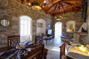 un soggiorno con pareti in pietra, tavolo e sedie di Villa Mandraki a Hydra