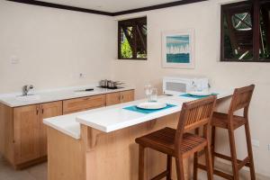 a kitchen with a counter with two chairs and a microwave at Santosha Barbados in Saint Andrew