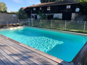 a swimming pool with blue water and a wooden deck at Gîte Proche du Bassin d'Arcachon in Mios