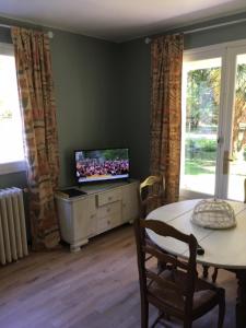 ein Wohnzimmer mit einem Tisch und einem TV auf einem Schrank in der Unterkunft Les Pierrottes pour 2 in Mornac