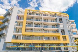 een geel gebouw met paraplu's ervoor bij Apartments Kristal Beach Nessebar in Nesebar
