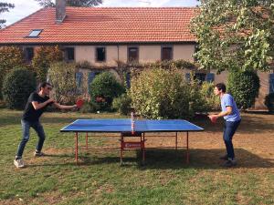 dos personas jugando ping pong en una mesa de ping pong en Le clos des artistes - Chambres d'hôtes, en Turny