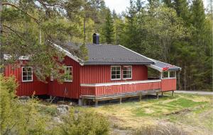 a red cabin in the middle of a forest at Awesome Home In Hemnes With Kitchen in Hemnes