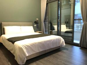 1 dormitorio con 1 cama grande y puerta corredera de cristal en HSR B&B en Zhongli