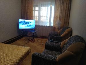 sala de estar con sofá y TV en Квартира 2-ух комнатная в центре города, en Ferganá