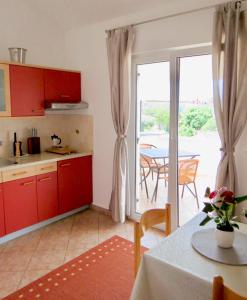 a kitchen with red cabinets and a table and a patio at Apartments Ljubica Veilchen in Funtana