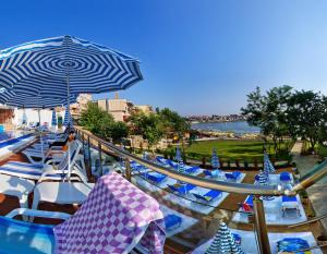 a bunch of blue and white chairs and an umbrella at Hotel Villa List in Sozopol