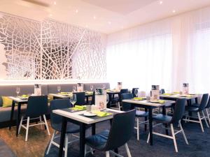 un comedor con mesas y sillas y una gran ventana en Mercure Stuttgart City Center, en Stuttgart