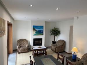 a living room with chairs and a table and a tv at Casa Oliveira in Vila do Conde