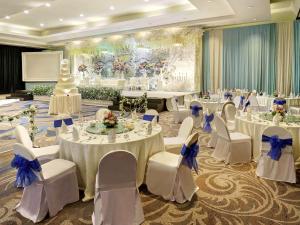 a banquet hall with white tables and white chairs at Mercure Convention Center Ancol in Jakarta