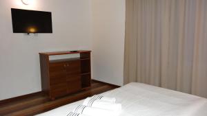 a bedroom with a bed and a dresser with a television at Vila Calypso Costinesti in Costinesti