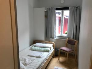 een slaapkamer met een bed, een stoel en een raam bij Vandrarhem Varvet in Ellös
