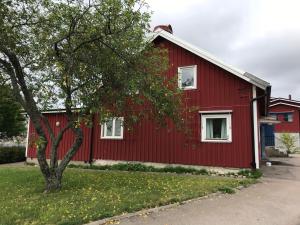 uma casa vermelha com uma árvore em frente em Vandrarhem Varvet em Ellös