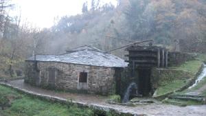 een oud stenen gebouw aan de zijkant van een heuvel bij Casa da Sapeira in Santa Eulalia de Oscos