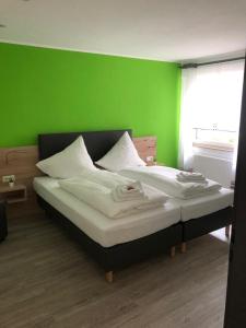 Un dormitorio con una pared verde y una cama en Hotel Unter den Linden en Kierspe