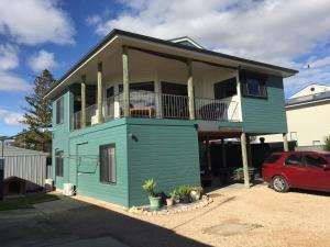 une maison bleue avec un balcon et une voiture rouge dans l'établissement The Jewel of the Bay, à Smoky Bay