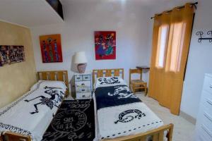 a bedroom with two beds and a table and a window at Appartamento vista mare - La Marmorata in Santa Teresa Gallura